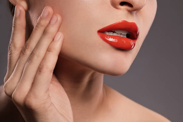 Close-up of a person with red lipstick touching their face, exploring red lip color suitability for all skin tones.