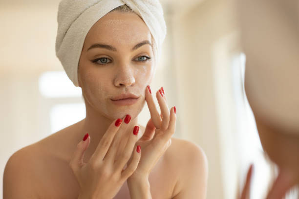 Woman applying cream to her face, illustrating skin care related to the skin microbiome.